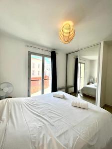 a bedroom with a white bed and a large window at Plaza Antibes one bedroom apartment with a parking spot in Antibes