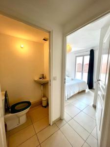 a bathroom with a toilet and a bed and a window at Plaza Antibes one bedroom apartment with a parking spot in Antibes