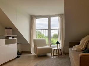 ein Wohnzimmer mit einem Sofa, einem Stuhl und einem Fenster in der Unterkunft Deluxe Apartments - Stuttgart Flughafen & Messe - Parkplatz in Stuttgart
