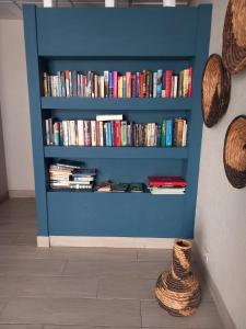 una estantería azul llena de libros junto a una pared en Monte Gordo Beach Sky Flat en Monte Gordo