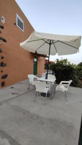 een tafel en stoelen met een parasol naast een gebouw bij Vivienda Vacacional El Pajar in Breña Alta