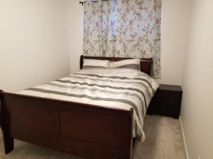 a bedroom with a bed with a wooden frame and a curtain at Newcastle. A Place you can call home in Edmonton