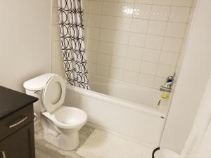 a bathroom with a toilet and a tub and a sink at Newcastle. A Place you can call home in Edmonton