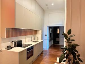 a kitchen with white cabinets and a potted plant at Luxurious 2-Bedroom, 2-Bathroom Paddington Retreat with En-Suite TV Bed in London