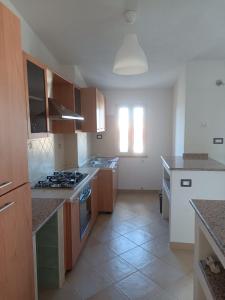 a kitchen with wooden cabinets and a stove top oven at Residenza Maria Antonia - Appartamento Francesco in Orosei