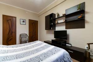 a bedroom with a bed and a flat screen tv at Nadezhda Apartments on Kazybek bi st. in Almaty