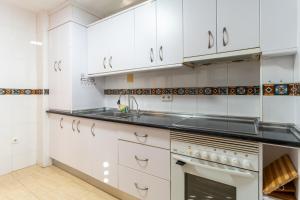 a kitchen with white cabinets and a sink and an oven at TrendyHomes Train Station in Almería