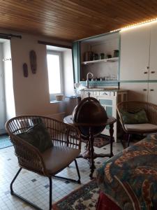 a living room with chairs and a table and a kitchen at la maison de Juliette En bas in Lascabanes