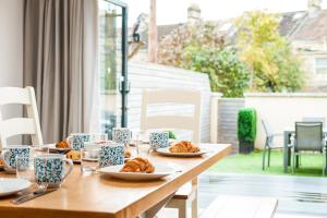 uma mesa de madeira com pratos de croissants em Solar Sanctuary- Skyline Balcony, City Centre, Three Floors, King Beds, Netflix and more! em Bath