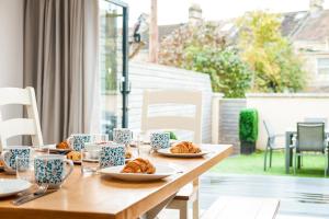 a wooden table with plates of croissants on it at Solar Sanctuary- Skyline Balcony, City Centre, Three Floors, King Beds, Netflix and more! in Bath