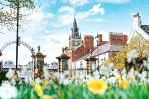 an old building with a clock tower and flowers at Bright Spacious Home with Parking - Haughton in Darlington