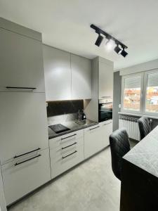 cocina blanca con armarios blancos y mesa en Apartman Loft 72, en Slavonski Brod