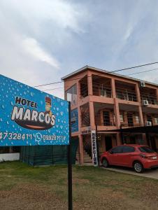 un panneau devant un bâtiment avec une voiture dans l'établissement Hotel Marcos Dayman, à Termas del Daymán