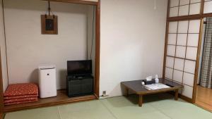 伊勢市にある海辺のゲストハウスーぽかぽか村ーのテレビ、テーブル、小さなテーブルサイドが備わります。