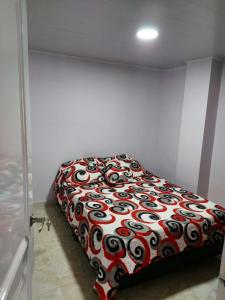 a bedroom with a bed with a red and white comforter at Lujoso apartamento amoblado a tan solo dos cuadras del parque principal. in Santa Rosa de Cabal