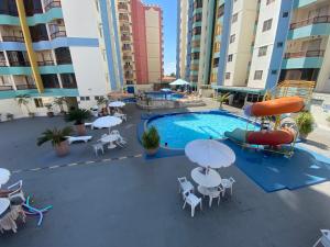 a swimming pool with tables and umbrellas and chairs at Apto 2 Quartos Caldas Novas Millennium com Wi-Fi in Caldas Novas