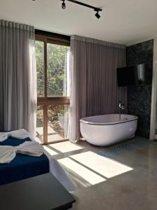 een grote badkamer met een bad en een raam bij Ecolounge Studios in Pirenópolis