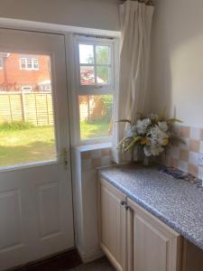 a kitchen with a door and a counter with flowers on it at Chessington Home Stay , 3 Bed 6 Guests Free Parking Near M25 JCT9, Chessington world of Adv Resort, Kingston, Epsom, Great for Families & Groups in Chessington