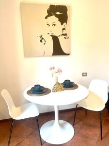 a white table with chairs and a painting on the wall at Avdkapartment in Milan