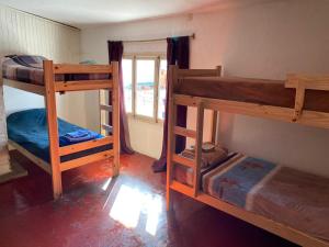 a room with three bunk beds and a window at Alojamiento Hospedaje Lodeolga "La Florida" in Rosario