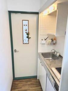 uma cozinha com uma porta branca e um lavatório em （201室) 成田机场附近宁静惬意的房子，8日以上免费接机 