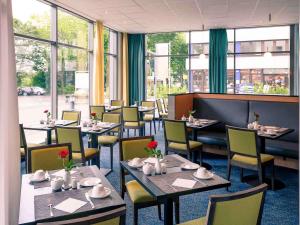 a dining room with tables and chairs and windows at Mercure Hotel Frankfurt Eschborn Süd in Eschborn