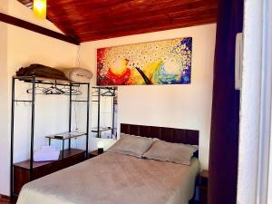 1 dormitorio con 1 cama y una pintura en la pared en Chalé Uyuni, en Alto Paraíso de Goiás