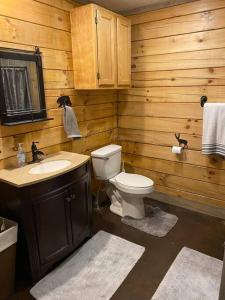 e bagno in legno con servizi igienici e lavandino. di Rustic Log Cabin at Swinging Bridge a Heber Springs