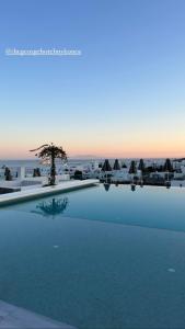 a large swimming pool with a view of the ocean at The George Hotel Mykonos in Platis Gialos