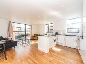 Bright Modern 2 Bed Apartment in East London في لندن: مطبخ كبير مع أجهزة بيضاء وغرفة معيشة