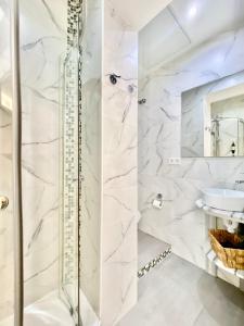 a white bathroom with a shower and a sink at Charming Puerta del Sol Center in Madrid