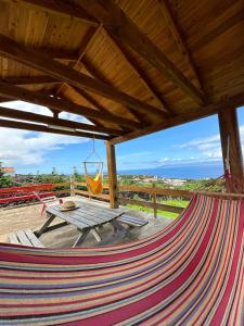 a hammock on a patio with a table and a view at Sara Village in São Roque do Pico