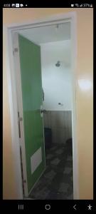 a bathroom with a green door in a room at BNJ Boarding House in Bislig