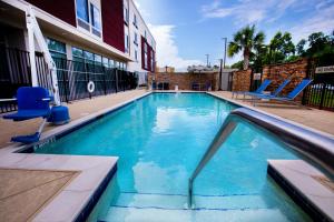 una piscina con sillas azules y un edificio en SpringHill Suites by Marriott Baton Rouge Gonzales, en Gonzales