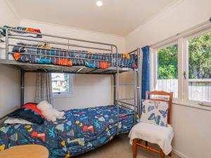 - une chambre avec des lits superposés et une chaise dans l'établissement Sunbathe Bach - Whitianga Holiday Home, à Whitianga