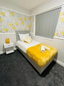 a bedroom with a bed with a yellow blanket at Alder House in Birmingham