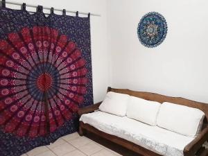 a living room with a couch and a mandala tapestry at Mandala casa 3 dorms cond fech piscina churrasqueira in Boicucanga
