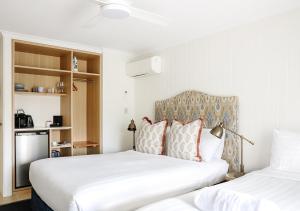 two beds in a room with two white beds at The Lord Byron in Byron Bay