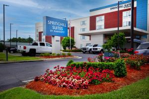 a sign for a hotel with flowers in front of a building at SpringHill Suites by Marriott Baton Rouge Gonzales in Gonzales