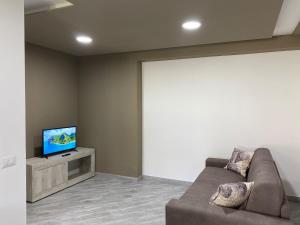 ein Wohnzimmer mit einem Sofa und einem Flachbild-TV in der Unterkunft Suite GuestHouse a pochi passi dal mare in Sassari