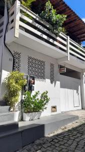 un bâtiment blanc avec des plantes en pot sur son côté dans l'établissement Suítes Recanto cama e café, à Arraial do Cabo