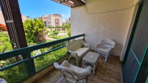 a balcony with chairs and a table and a window at Chalet in Mena 4 in Dawwār ‘Abd al ‘Aţī Abū ‘Ajūz