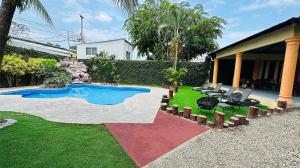 podwórko z basenem i krzesłami oraz dom w obiekcie H4 LAS CABAÑAS w mieście Corozal