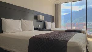 a hotel room with two beds and a large window at HOTEL CHACAO SUITES in Caracas