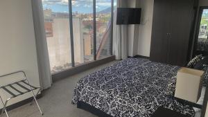 - une chambre avec un lit noir et blanc et une fenêtre dans l'établissement HOTEL CHACAO SUITES, à Caracas