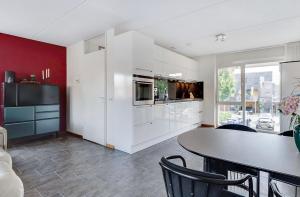 a kitchen with white cabinets and a table with chairs at Chico in Almere