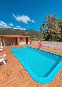 a person standing next to a large blue swimming pool at Casa de campo com Piscina in Santo Amaro da Imperatriz