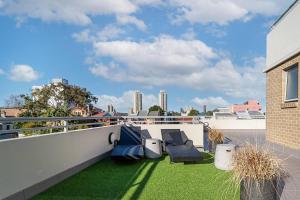 a balcony with green grass and chairs on a building at 'Redfern Horizons' An Unforgettable Rooftop Escape in Sydney