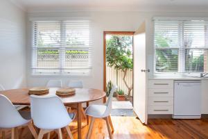 シドニーにあるFamily Stay with Idyllic Sun-drenched Courtyardのキッチン(木製テーブル、白い椅子付)