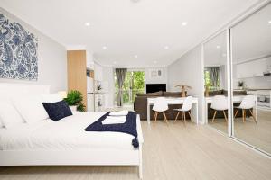 a bedroom with a white bed and a dining room at 'The Crows Nest' Spacious Studio with Balcony in Sydney